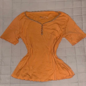 Orange topp - Jättefin orange topp / tshirt med knappar. Väldigt somrigt men passar absolut till höst och vår. Passar S-L beroende på önskad passform. Hade även varit enkel att sy in