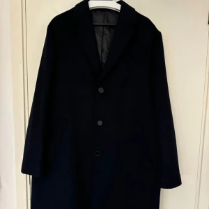 Marinblå kappa - En superfin marinblå kappa i ullmix. Kappan har aldrig använts och är helt ny. Köpt för 799kr, mitt pris 450kr.