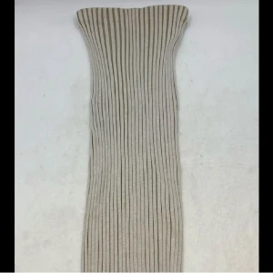 Beige axelbandslös klänning - Säljer en superfin beige kjol med ribbad design. Perfekt för både fest och vardag! Den är tight och framhäver figuren på ett snyggt sätt. Passar perfekt till sommarens alla tillfällen.