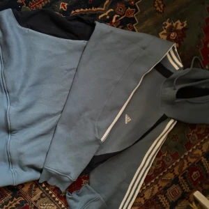 Adidas tröja  - Adidas tröja i storlek L. Men passar även den som har M. Använd ett fåtal gånger så den är nästan som ny. Tröjan är ljusblå med svarta och vita detaljer.