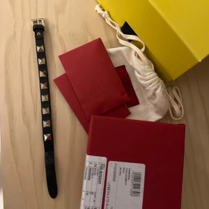 Valentino armband  - Valentino armband, svart med guldiga nitar. I jättefint skick förutom en liten slitning (se bilder) kommer i orginalbox med kvitto!