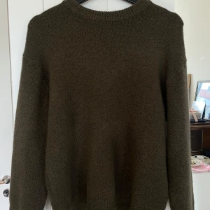 Olivgrön stickad tröja - Säljer en supermysig mörkgrön stickad tröja som är perfekt för både höst och vinter. Tröjan är i normal passform och känns riktigt skön mot huden.