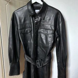 Läderjacka Zara - Säljer min fina läder/skinnjacka från Zara. Jättefint skick och används inte. Slitsar på sidorna och knytband i midjan. Snygg att ha i höst🍂 Skriv vid funderingar 