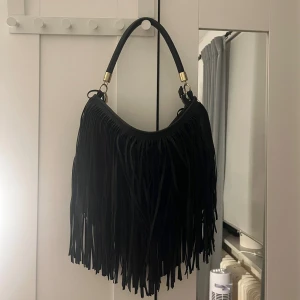 Svart h&m handväska  - Helt oanvänd hm väskan med volanger  som kan andvändas som både axelväska och sidoväska. Skriv för fler frågor :)