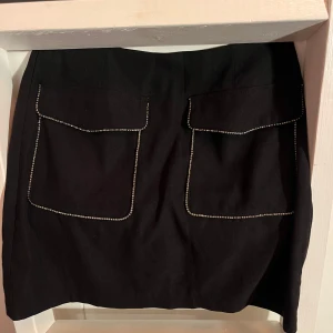 Set med matchande kjol och skjorta - Svarta matchande kjol och skjorta med strass runt detaljerna, perfekt till nyår eller fest! Saknar lappar men jag bär strl 36 i annat fall. Skicka ett meddelande om du undrar något eller ett bud om du är sugen! 