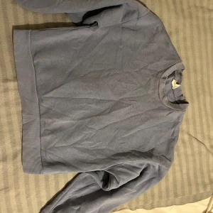 Grå sweatshirt - Säljer en stilren grå sweatshirt med rund hals och långa ärmar. Perfekt för en avslappnad look. Ribbstickade muddar vid ärmslut och nederkant ger en skön passform. Är ifrån Ginatricot storlek Xs