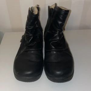 Rieker  boots med dragkedja - Säljer ett par svarta Rieker boots med dragkedja på sidan st.37.De har en robust sula och är fodrade för extra värme. Perfekta för kyligare dagar.