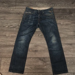 Mörkblå jeans från Replay - Säljer ett par mörkblå Replay Waitom jeans med klassisk femficksdesign. Jeansen har en straight passform och är perfekta för en avslappnad stil. De har en snygg tvättad look och är tillverkade i slitstarkt denim.