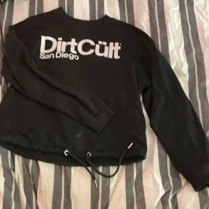Svart tröja från DirtCült - Säljer en svart DirtCult tröja som är i ganska bra skick förutom att det är en liten fläck längst ner på tröjan ( se sista bilden ). Jag vet inte om fläcken går bort än men jag kan försöka få bort den. Storlek S, ganska normal i storlek. Den är lite som en magtröja då den inte är lika lång som en hoodie och den går att knyta vid magen. Hör av dej vid intresse eller för frågor. Köparen betalar frakten💕