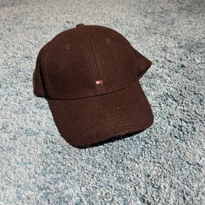 Svart keps från Tommy Hilfiger - Snygg svart keps med en liten broderad logotyp framtill. Perfekt för en stilren look. Justerbar passform med spänne baktill.