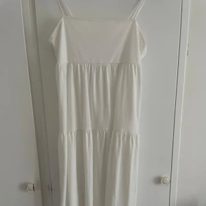 Vit axelbandslös klänning - Säljer en vit lång klänning från hm i storlek 170 (sitter som xs-s). Den är använd 1 gång på skolavslutningen. ( kan sänka priset mycket)
