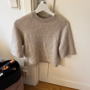 Beige stickad tröja - Mysig beige stickad tröja med korta ärmar och rund hals. Perfekt för lager-på-lager under kyligare dagar. 