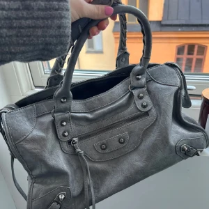 Grå handväska med dragkedja - Super snygg grå handväska med detaljerade sömmar och dragkedja. Väskan har två handtag och en praktisk ytterficka med dragkedja. Perfekt för att bära dina dagliga prylar med stil såklart!💗✨✨