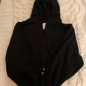 Svart hoodie med dragkedja - Säljer en svart hoodie med dragkedja och huva. Super skön och passar perfekt att bara ha hemma. Lite kortare i längden vilket gör den assnygg!⭐️