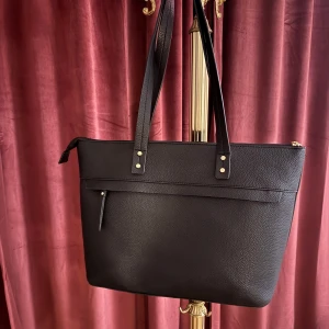 Svart axelväska från Don Donna - Snygg och stilren svart axelväska från Don Donna i syntetmaterial. Väskan har en praktisk dragkedja och långa axelremmar för bekväm användning. Perfekt för att bära med sig det nödvändigaste med stil💗💗Ursprungspris 499kr säljer för billigare