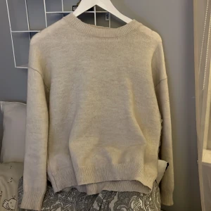 Beige stickad tröja - Mysig beige stickad tröja med rund hals och långa ärmar. Perfekt för kyligare dagar och enkel att matcha med olika outfits.