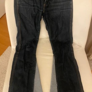 Mörkblå jeans från Wrangler (W28, L34) - Säljer ett par mörkblå jeans från Wrangler med snygga sömmar. Tillverkade i bomull med lite stretch. Jag har själv sytt bootcuten i ett ljusblått jeanstyg.
