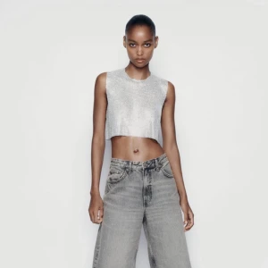 Silvrig croppad topp - Trendig topp i metallic med glitter. Perfekt för en kväll ute eller en speciell tillställning. Den är ärmlös och med sin glittrig yta fångar den  ljuset snyggt. 