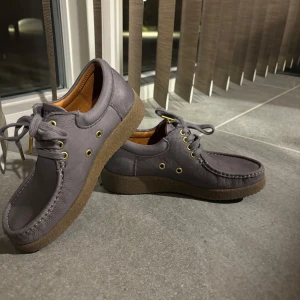 Grå skor från Nature - Säljer ett par grå skor från Nature med snörning och en robust sula. Skorna har en stilren design med guldfärgade öljetter och en bekväm passform.