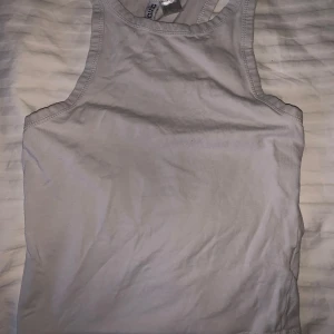 Vit linnetopp från H&M Divided - Säljer en enkel och stilren vit linnetopp från H&M Divided. Perfekt för varma dagar eller som lager under andra plagg. Toppen har en klassisk design med rund halsringning.