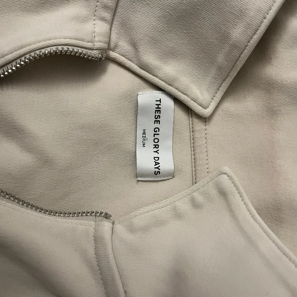 Säljer en stilren beige tröja från These Glory Days i storlek medium. Tröjan har en dragkedja vid halsen och långa ärmar. Perfekt för en avslappnad look. Tröjan har en defekt på höger arm vilket är därför priset är sänkt. Tröjan är använd ett fåtal gånger.. Neuletakit & Villapaidat.