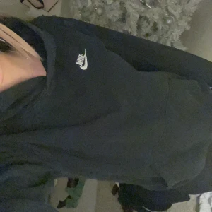 Svart hoodie från Nike - Säljer en klassisk svart hoodie från Nike med vit logga på bröstet. Tröjan har en bekväm passform och långa ärmar, perfekt för en avslappnad stil. Hör av dig vid intresse!