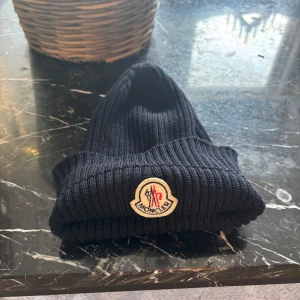 Mörk blå  mössa från Moncler - Snygg svart  mössa från Moncler med broderad logotyp framtill. Perfekt för kyliga dagar och ger en stilren look. Skriv vid frågor eller funderingar 