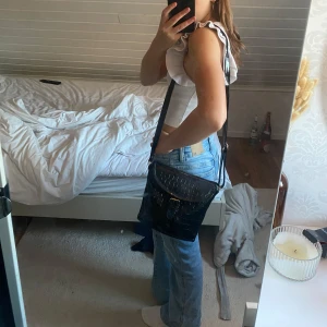 Svart axelväska -  Svart axelväska med ficka inuti och långt band