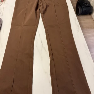 Bruna kostymbyxor från H&M - Bruna kostymbyxor från h&m i storlek 48. Iprincip oanvända. Byxorna har dragkedja på sidan, en ficka på baksidan och slits i ändarna🙂