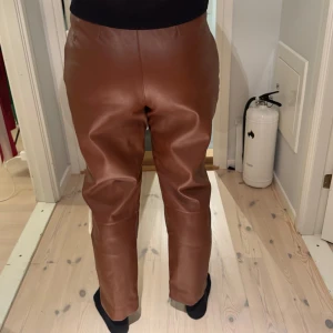 Bruna skinnbyxor - Snygga bruna skinnbyxor med hög midja och rak passform.. Byxorna har en klassisk design utan extra detaljer.