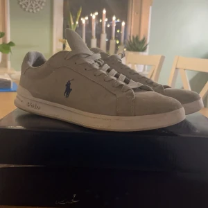 Ralph lauren mocka skor - Snygga grå sneakers från Polo Ralph Lauren med klassisk design och snörning. Skorna har en diskret logotyp på sidan och är perfekta för en stilren look. Strl 42 skicket är bra