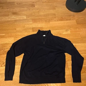 Mörkblå tröja med dragkedja från Lindex - Säljer en mörkblå tröja från Lindex med dragkedja och hög krage. Perfekt för kyliga dagar. Tröjan har långa ärmar och är tillverkad i ett mjukt material.