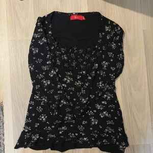 Svart blommig blus/tröja - Charmig svart topp med vita blommor och volangdetaljer. Den har en smockad överdel som ger en bekväm passform och korta ärmar!❤️Är i storlek xxs-xs och säljer för den inte passar längre ❤️