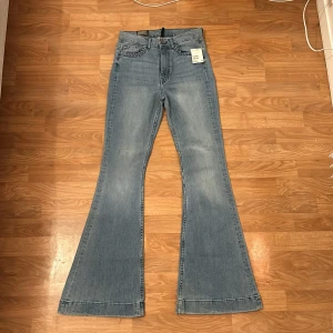 Blå flare jeans från H&M Divided - Snygga blå flare jeans från H&M Divided med hög midja. Aldrig använda med etikett på. Perfekta för en trendig look med sin utsvängda stil. Klassisk femficksdesign och dragkedja i gylfen. Inga fläckar eller slitage. 