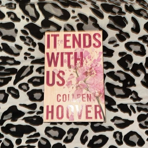 It Ends With Us - Boken 'It Ends With Us' av Colleen Hoover har en omslagsdesign med rosa blommor och stora röda bokstäver. Den handlar om kärlek och de svårigheter som kan uppstå i relationer. Perfekt för dig som gillar känslosamma och gripande berättelser.