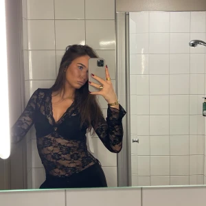 Svart spetsblus - Snygg svart spetsblus med blommigt mönster och v-ringad design. Blusen har långa ärmar och är perfekt för en elegant look.