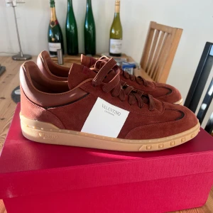  Valentino Upvillage - Snygga vinröda sneakers från Valentino Garavani i mocka. Skorna har en klassisk design med snörning och en bekväm gummisula. Perfekta för en stilren look.
