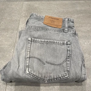 Grå jeans från Jack & Jones - Säljer ett par grå jeans från Jack & Jones i loose fit.Jeansen är i bra skick. Skriv vid funderigar storlek 31/30
