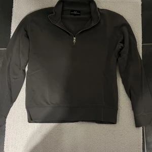 Grå  tröja med dragkedja  - Snygg grå tröja med halv dragkedja och hög krage. Perfekt för en stilren look. Tröjan har långa ärmar och en bekväm passform. 