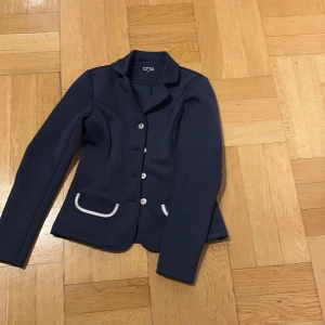 Mörkblå kavaj från CRW - Snygg mörkblå kavaj från CRW med vita detaljer och knappar framtill. 