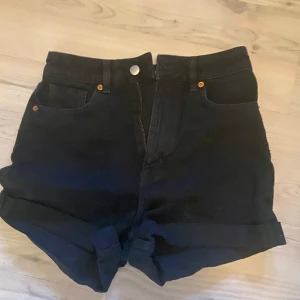 Svarta högmidjade shorts från H&M - Snygga svarta högmidjade shorts från H&M med klassisk femficksdesign och uppvikta ben. Perfekta för en stilren look. Priset går att diskutera💗