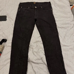 Svarta jeans från Lee - Snygga svarta jeans från Lee med klassisk design och dragkedja. Perfekta för en stilren look. De har en normal passform och är tillverkade i slitstarkt material.