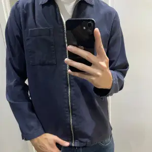 En navyblå overshirt från East West är en trendig och mångsidig jacka. Den har en avslappnad passform och är tillverkad av högkvalitativt material som är perfekt nu i höst. Perfekt att använda som ett lagerplagg över en t-shirt, tröja eller skjorta ✅