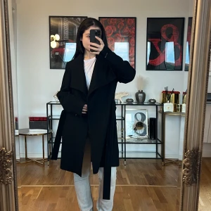 Svart kappa från Calvin Klein 💞 - Säljer en elegant svart kappa från Calvin Klein. Den har en stilren design med ett bälte i midjan och långa ärmar. Perfekt för höst och vinter, och den ger en sofistikerad look till vilken outfit som helst. Kappan är i bra skick och redo för nya äventyr!