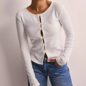 Ribbad topp med rosetter NELLY - Slutsåld topp från Nelly, helt oanvänd, med lapp kvar. Storlek S. Originalpris 299kr men finns som sagt inte kvar på hemsidan. 