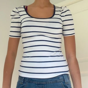 Randig topp från 365 Sunshine - Säljer en superfin vit och marinblå randig topp från 365 Sunshine. Den har en rund halsringning och korta ärmar. Perfekt för en avslappnad sommarlook eller en dag på stan. Toppen är i bra skick och passar perfekt till jeans eller kjol!