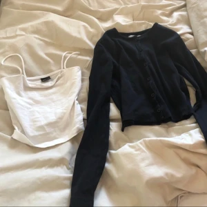 Vit linnetopp och svart kofta - Säljer en söt vit linnetopp med smala axelband och en svart kofta med knappar. Linnetoppen är perfekt för sommardagar och koftan är ett bra komplement för kyligare kvällar. Båda plaggen är i bra skick och kan stylas tillsammans eller var för sig.