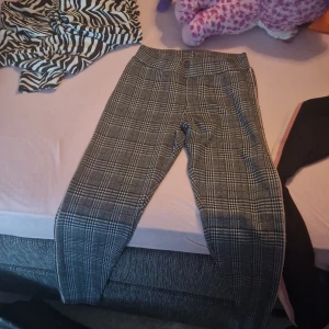 Rutig byxa från Lindex - Säljer ett par snygga rutiga byxor från Lindex i storlek EUR 170. De är i en klassisk svart och vit färgkombination med ett stilrent rutmönster. Perfekta för både vardag och fest!
