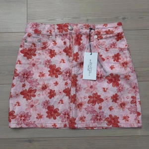 Blommig kjol från NA-KD - Blommig kjol från Misslisibells kollektion med NA-KD i rosa och röda toner. Oanvänd och är i storlek 34. 