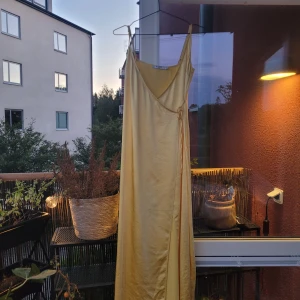 Gul långklänning  - Gul satinklänning. Har använts till bal. Se bild 2 för defekt.  Min fru är 155cm och behöver 10cm klackar för att inte släpa i marken. 